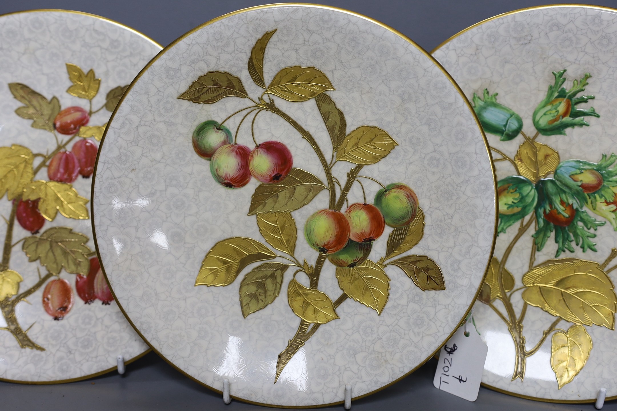 Three Royal Worcester Aesthetic period plates, with raised gilded and enamelled botanical decoration, on a floral ground, originally retailed by Gardner’s Strand, London. 23cm diameter.